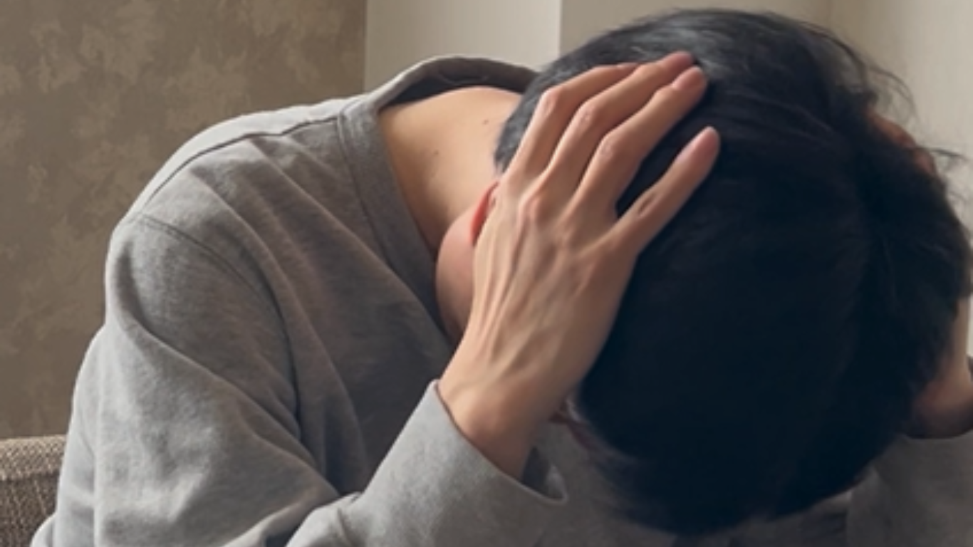 うつむいて両手で頭を抱える男性