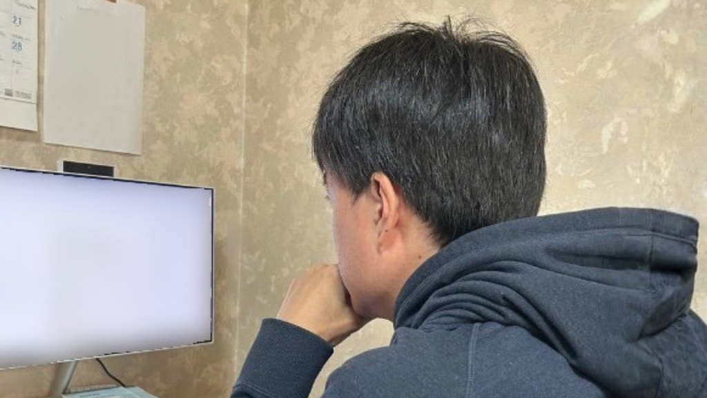 自宅でパソコンの画面に向かう男性の後ろ姿