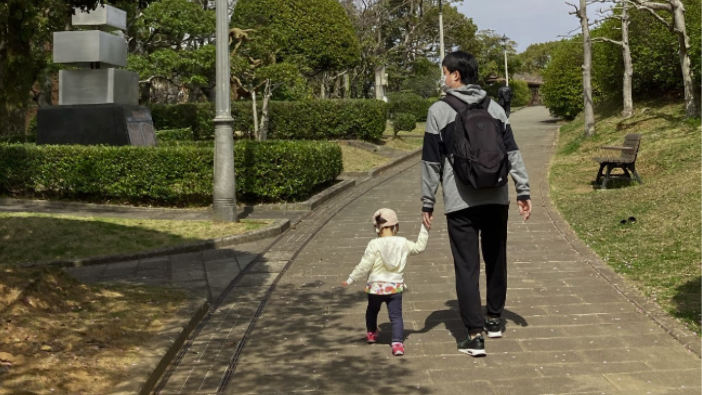 公園で手をつないで歩く親子の後ろ姿